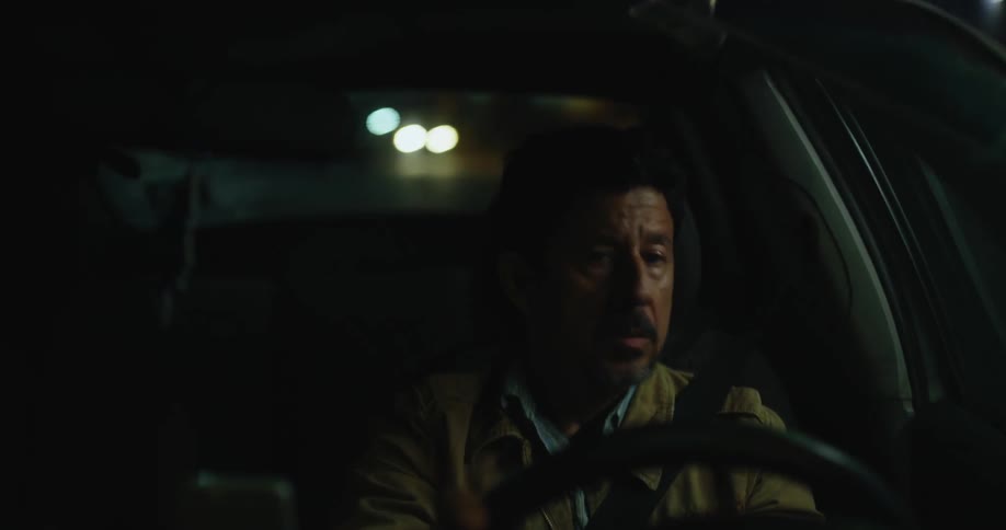 A man driving a vehicle looks around at his surroundings while turning the steering wheel
