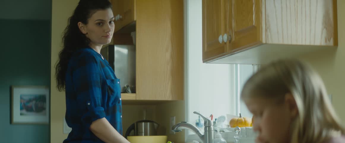 Mom pauses washing dishes to look over at her daughter