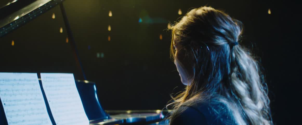 A teenager looks a bit anxious as she plays the piano on stage