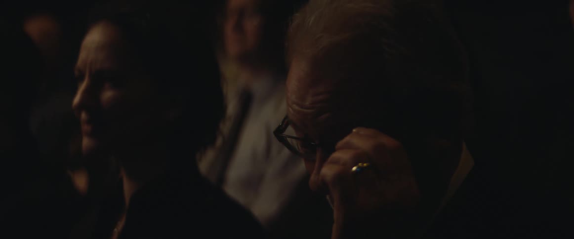 A man smiles and cries as he sits watching an event