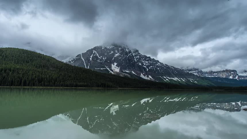 Clouds pass over a snowy mountain lake