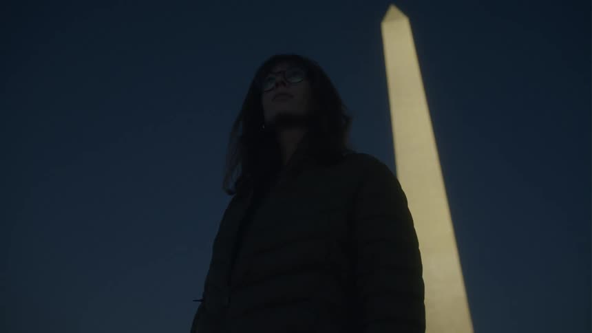 A woman is looking around by the tower