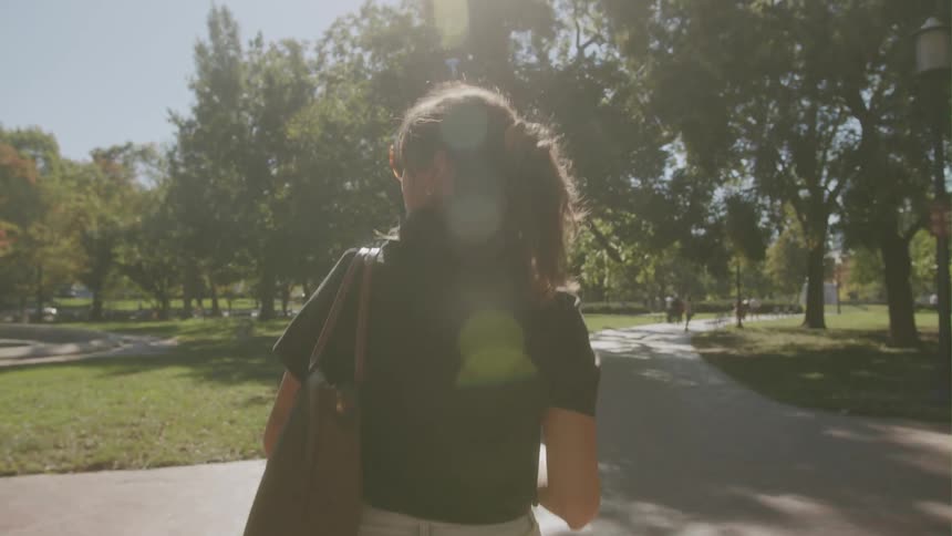A woman looks to her left while walking on a trail in a park