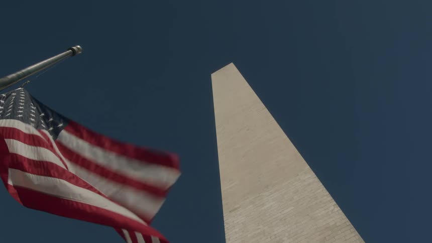 American flag waves in the wind near the base of the washington monument