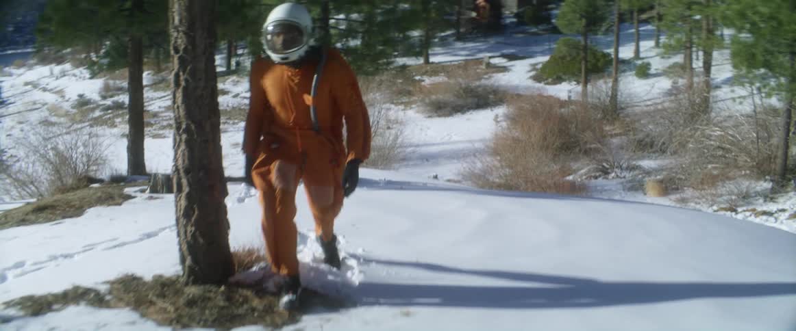 A person is walking outdoors in winter and wearing a space suit