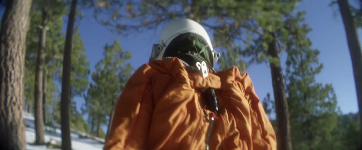A person is walking through a forest and wearing a helmet