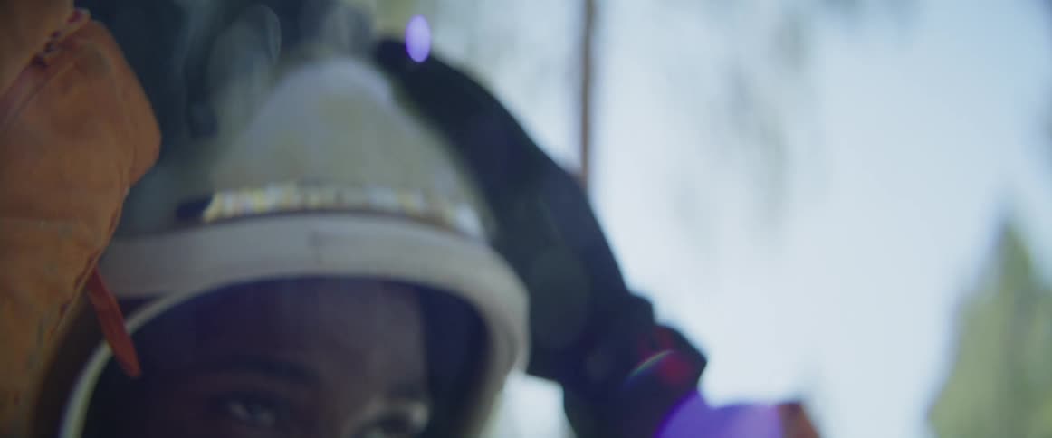 A man puts down the face guard of his helmet while standing up in a forest