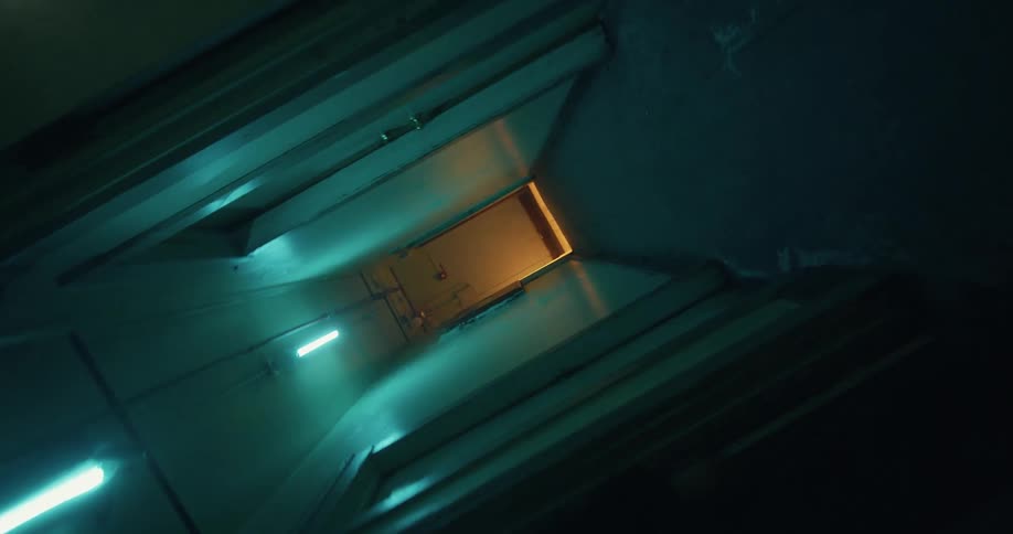 A woman walks down a dimly lit hallway in an apartment building