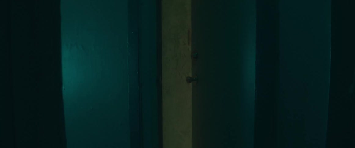 A door slowly swings open in a dimly lit corridor