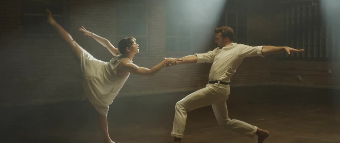 A man and a woman are dancing together as a spotlight shines on them