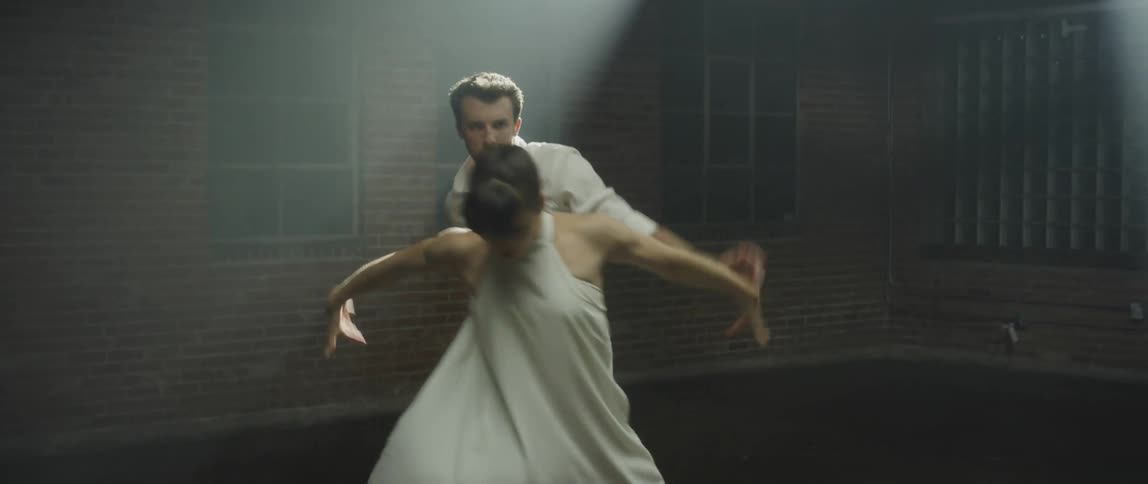 A man and a woman are dancing together as a spotlight shines on them