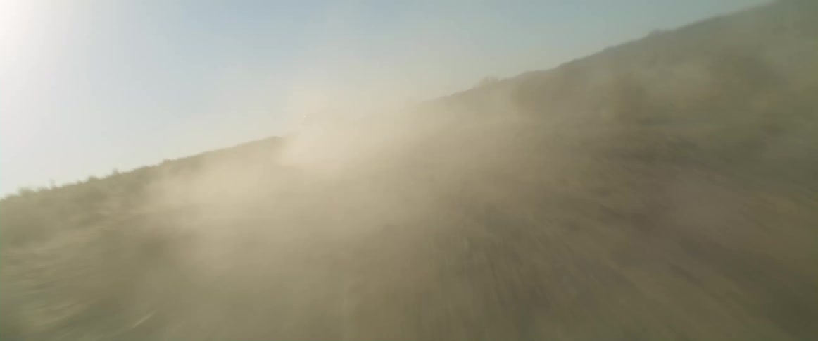 A car is driving off road through a rural area