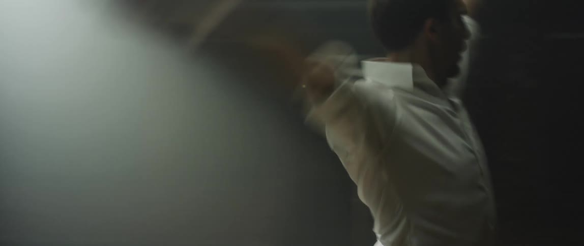 A pair of dancers dance together in a dimly lit room