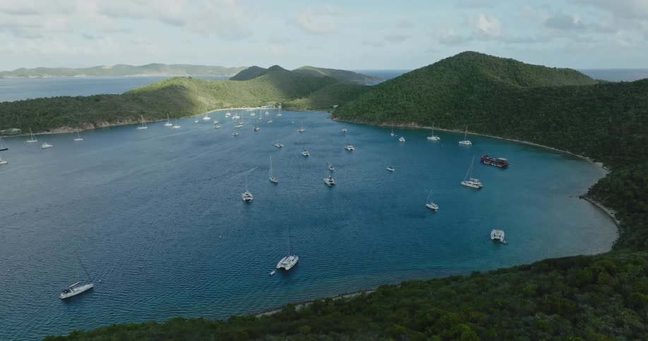 Many boats are sailing off the coast under a cloudy sky