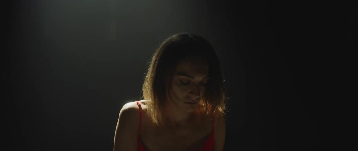 A woman wearing a red evening dress is on stage playing a piano