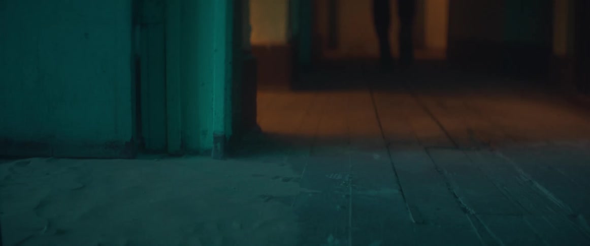 Person wearing boots walk through doorway as dust is blown into the building