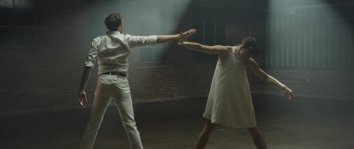 Spotlights shine on two dancers as they perform a contemporary dance on stage