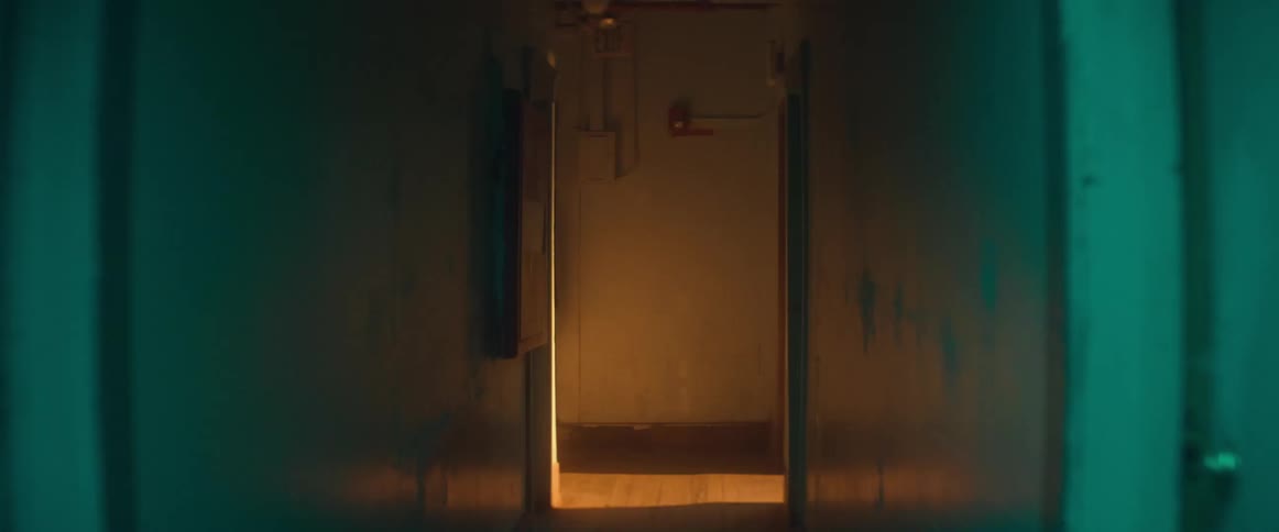A woman walks down a dimly lit hallway in an apartment building