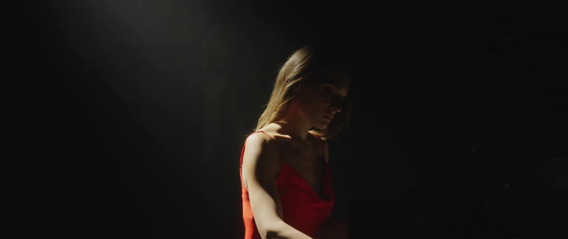 A woman plays the piano on stage under a bright spotlight
