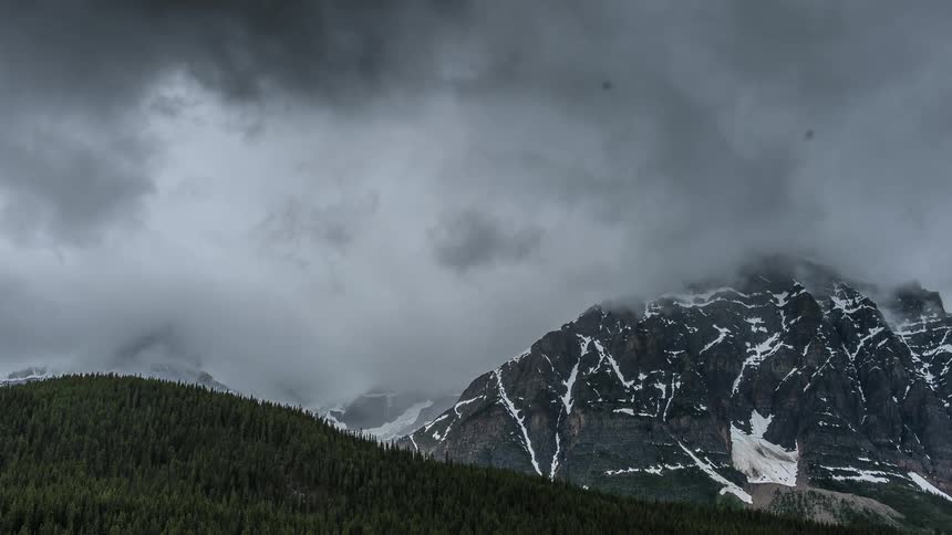 Clouds form over mountains with snow