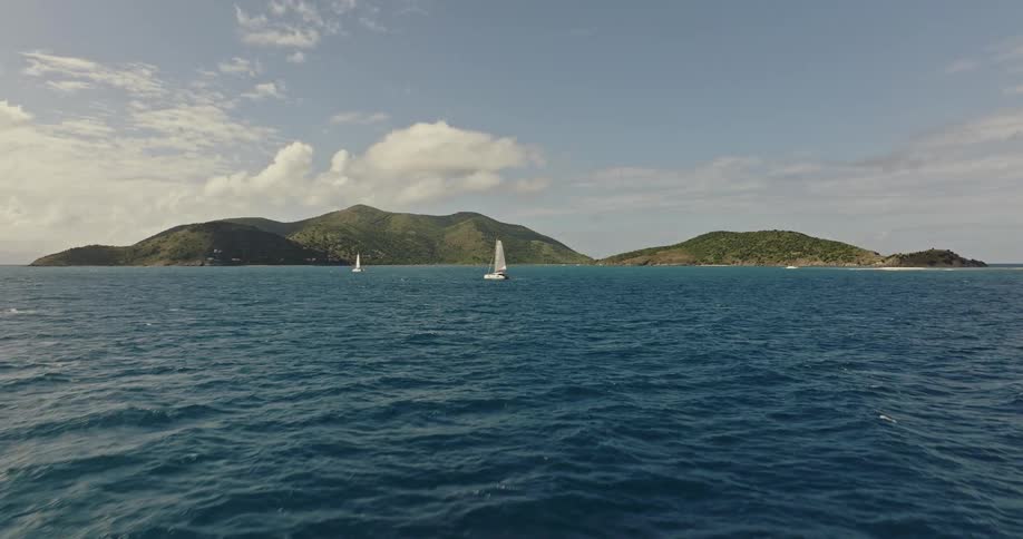 Boats sail off the coast of a land mass during the day
