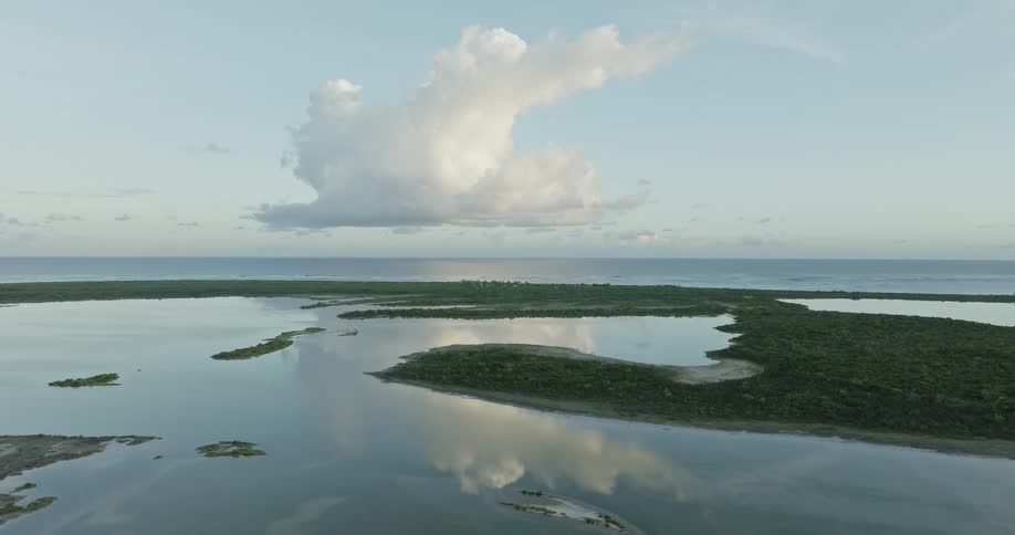 Mirror like water surface bordering peninsula reflects clouds in the sky