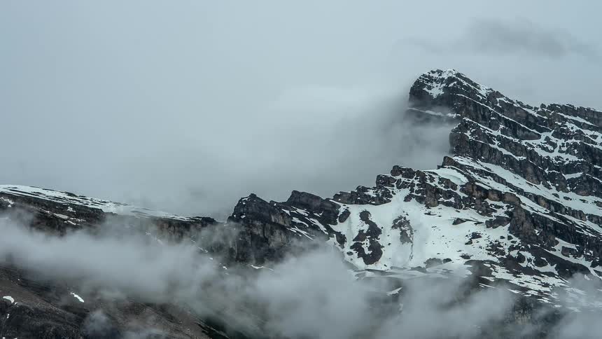 Clouds move around on a snow covered mountain top