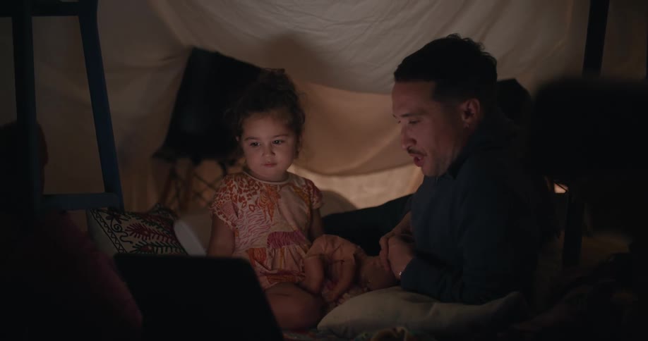 A father and daughter watch the laptop together