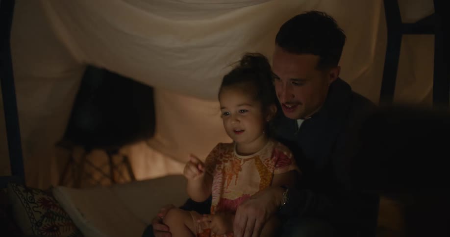 Father with mustache black shirt and jeans and holds daughter and watches laptop in room