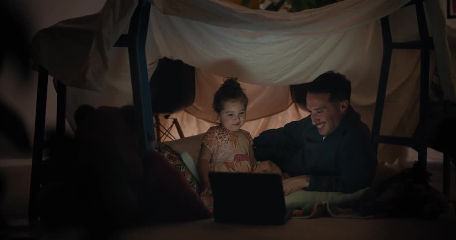 A father and child watch the laptop together