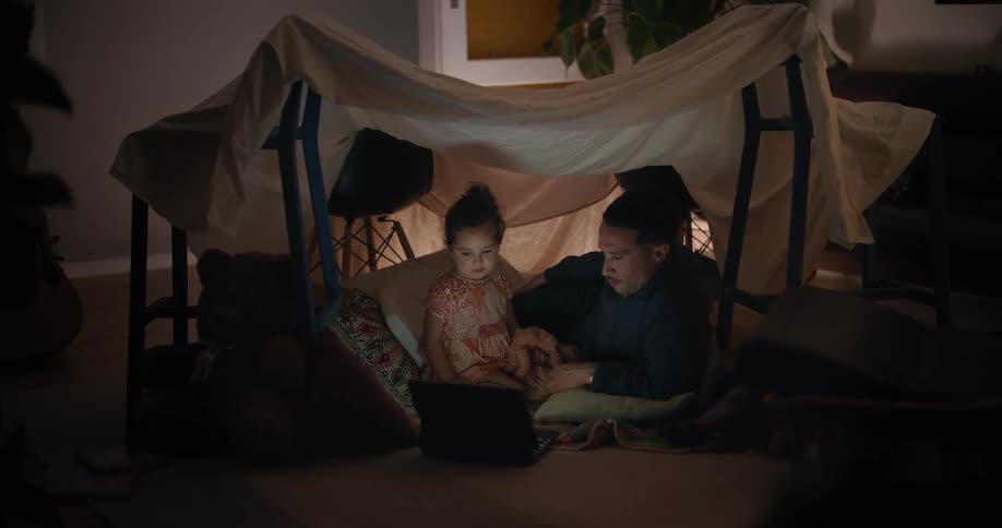 A child and man watch the laptop together