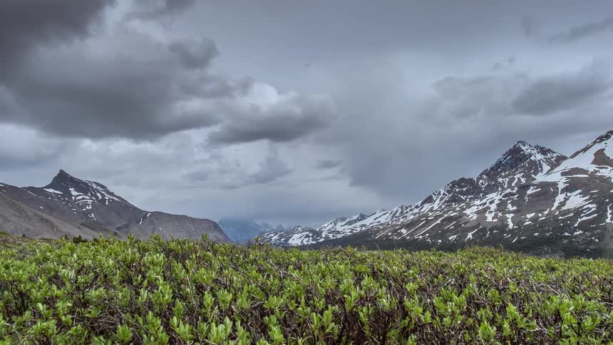 Time lapse of clouds moving over a field and mountain range