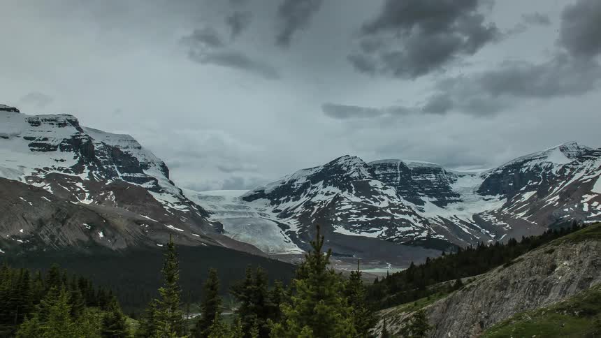 Storm clouds move over a mountain range during the day