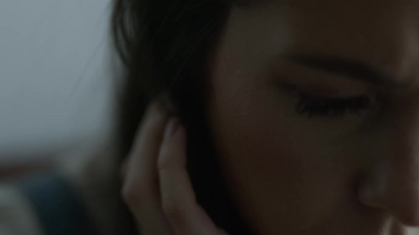 Woman combs her hair back with her hand as she looks down studiously