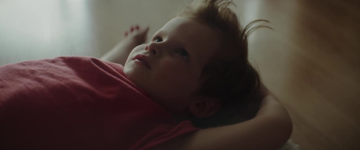 A child is laying on a carpet indoors during the day time