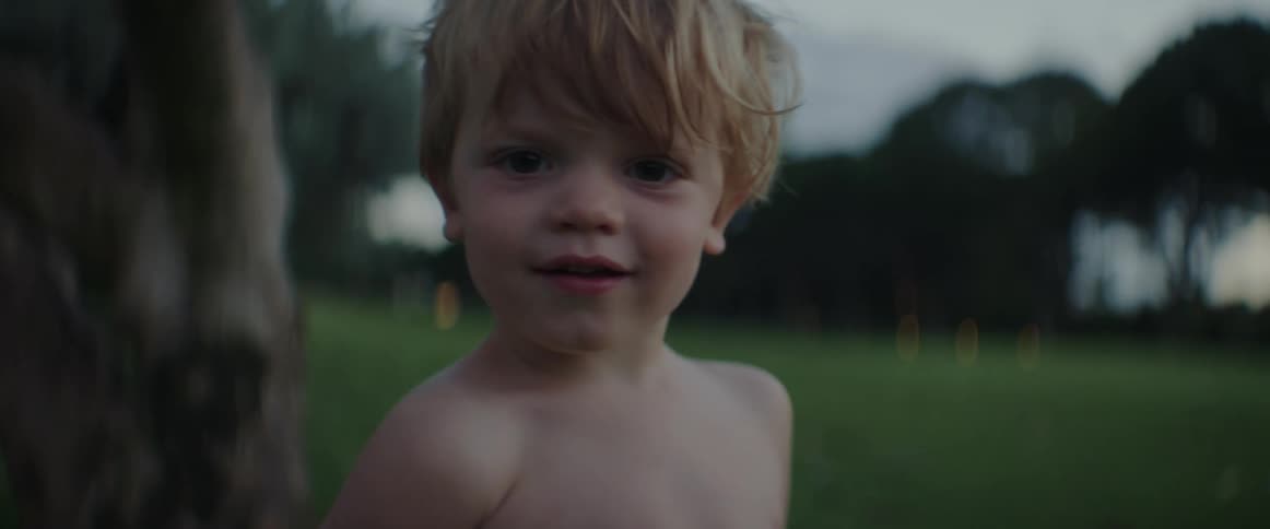 A boy turns and runs toward his siblings in the backyard