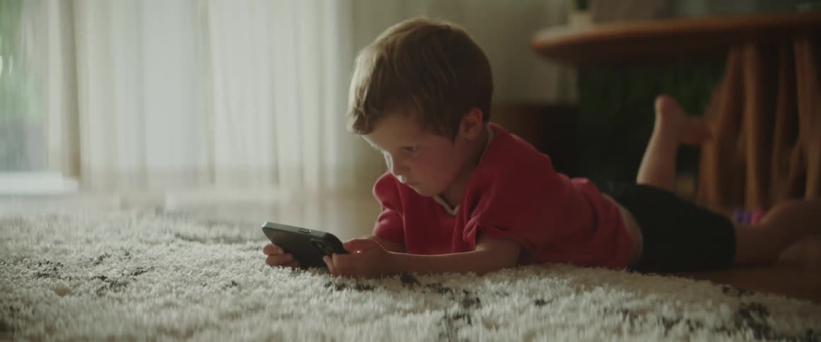 A child is laying on the ground and playing video games