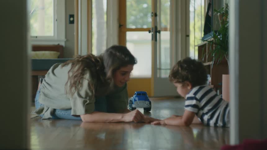 A woman counts her fingers while sitting on the floor with her son