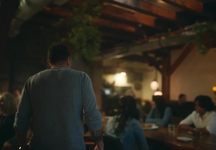 A mans friends cheer when he sits down to join them in a restaurant