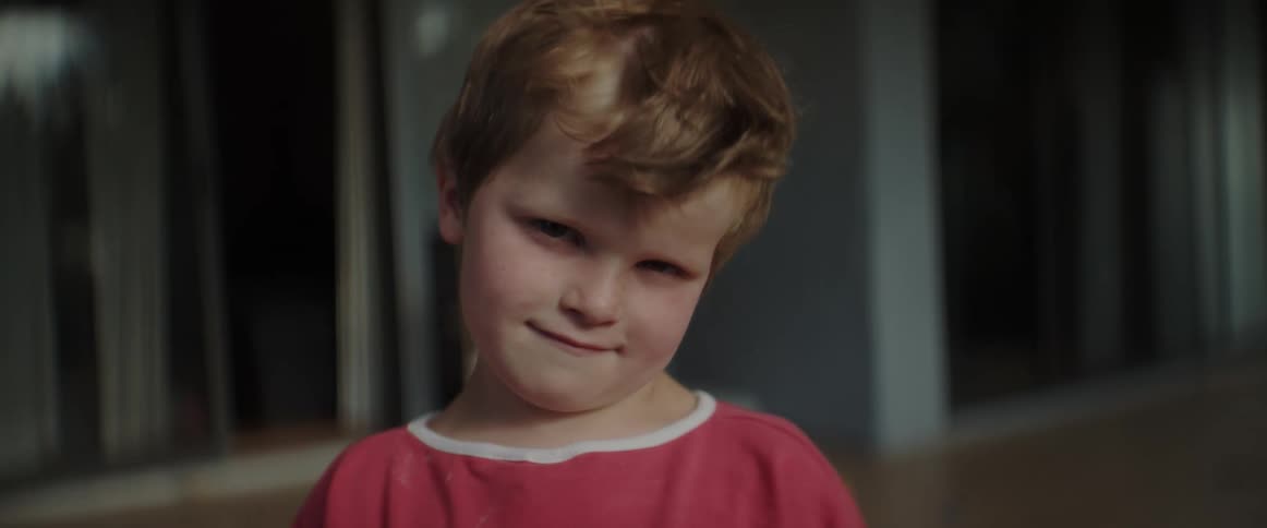 A young boy looks angrily into the camera while wind blows through his hair
