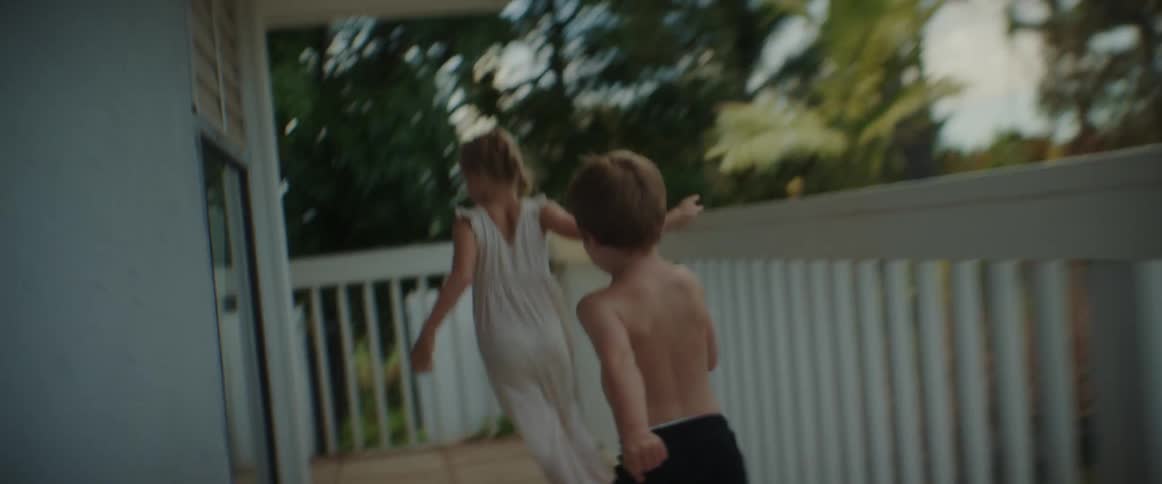 Children chase each other around the porch