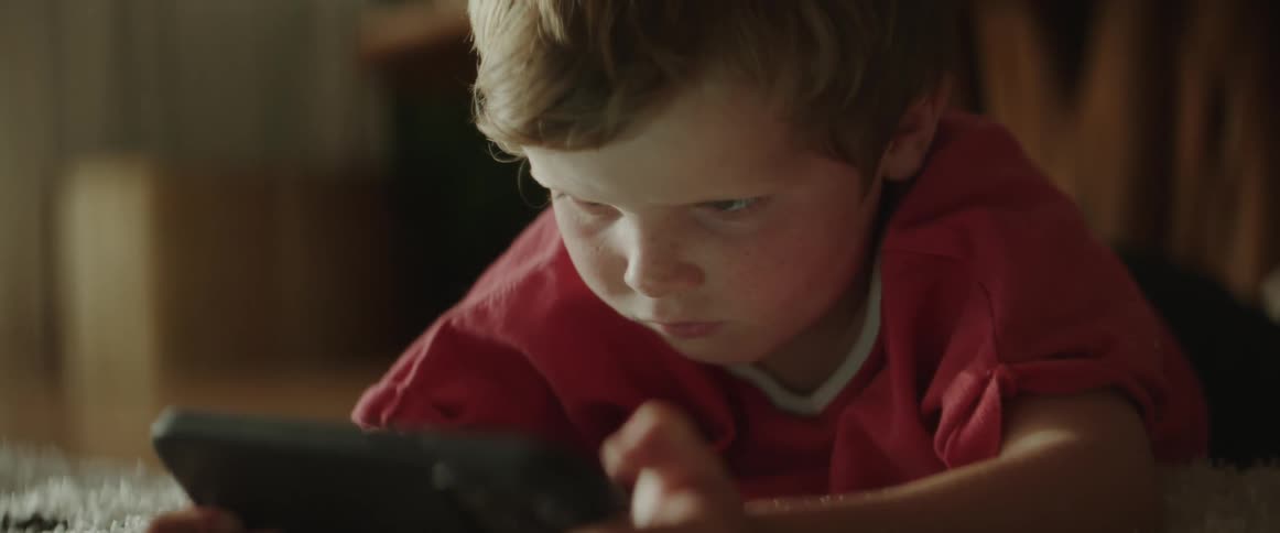 A child is watching something on a cell phone