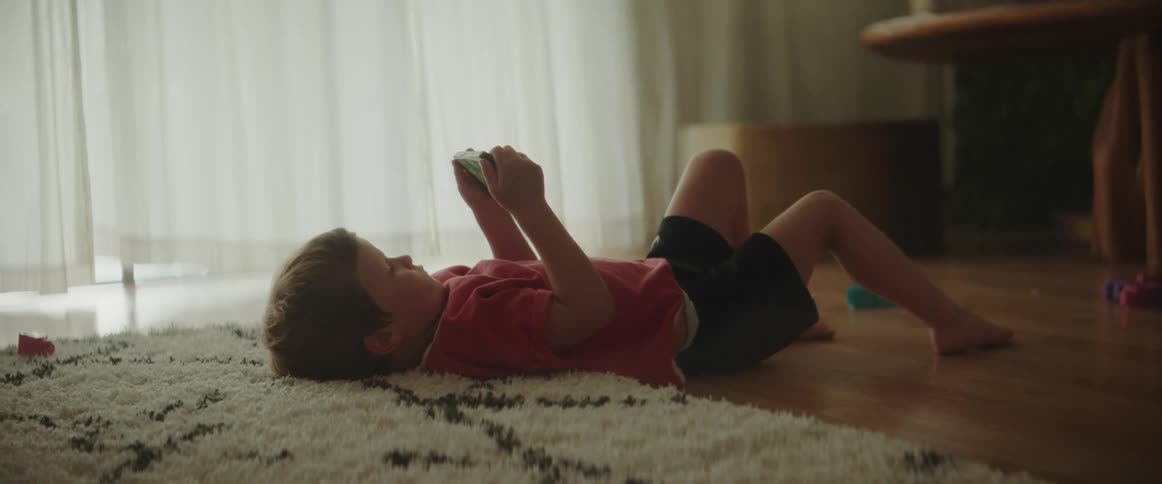 A child is watching the iphone on the floor
