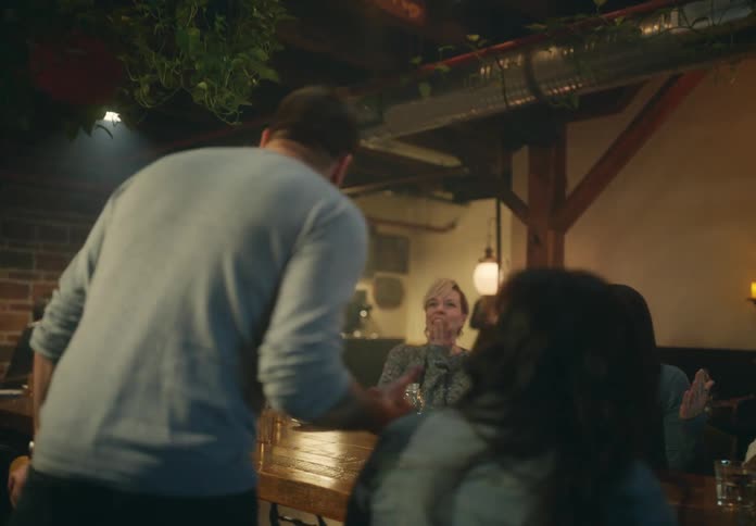 A man enters the restaurant and sits down with friends to eat and drink