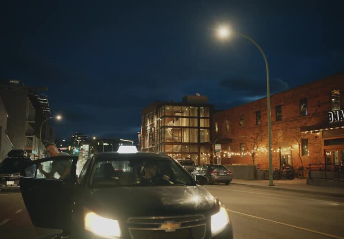 A person is getting out of a car and crossing the street in a city