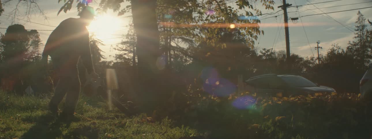 A man is doing yard work in his front lawn at dusk