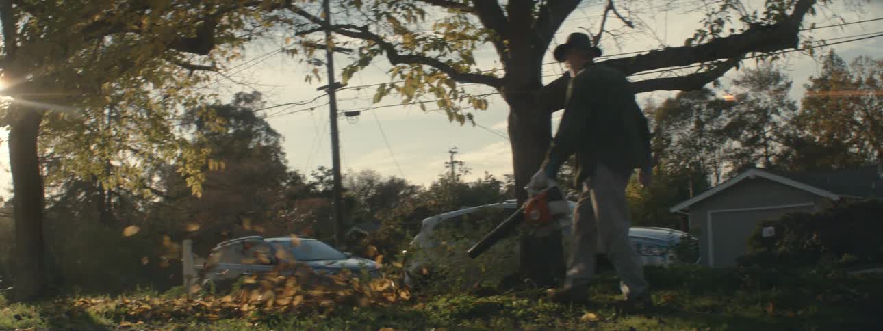 A landscaper is blowing the leaves on the lawn