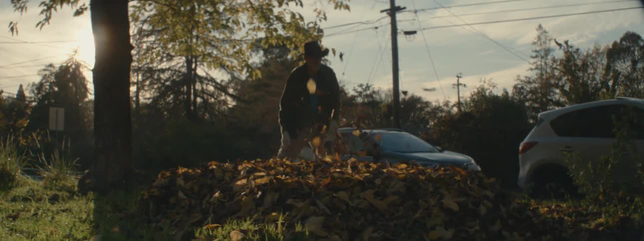 A man is blowing the leaves into a pile