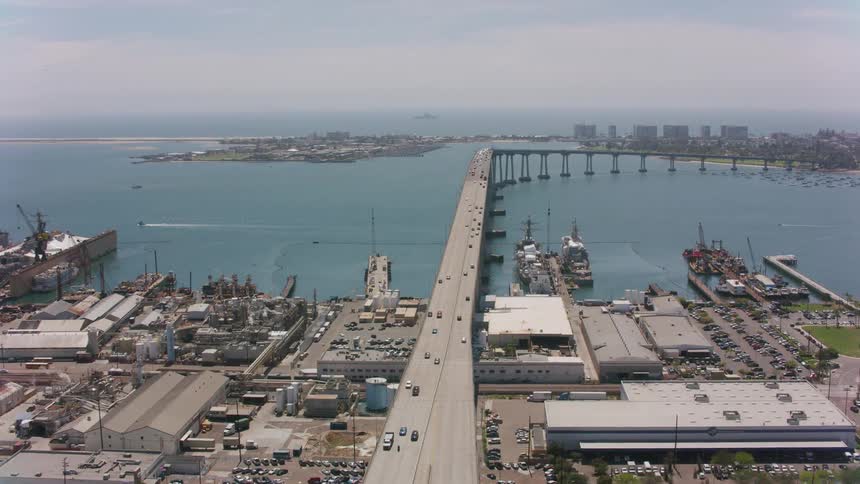 Traffic travels across a large bridge spanning a waterway in a city during the day