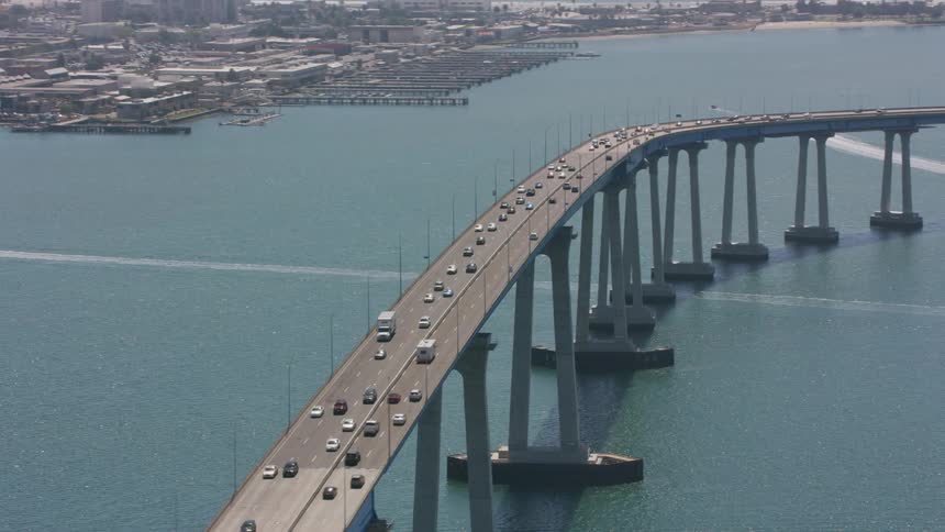 Traffic moves across a bridge as boats sail on the water below